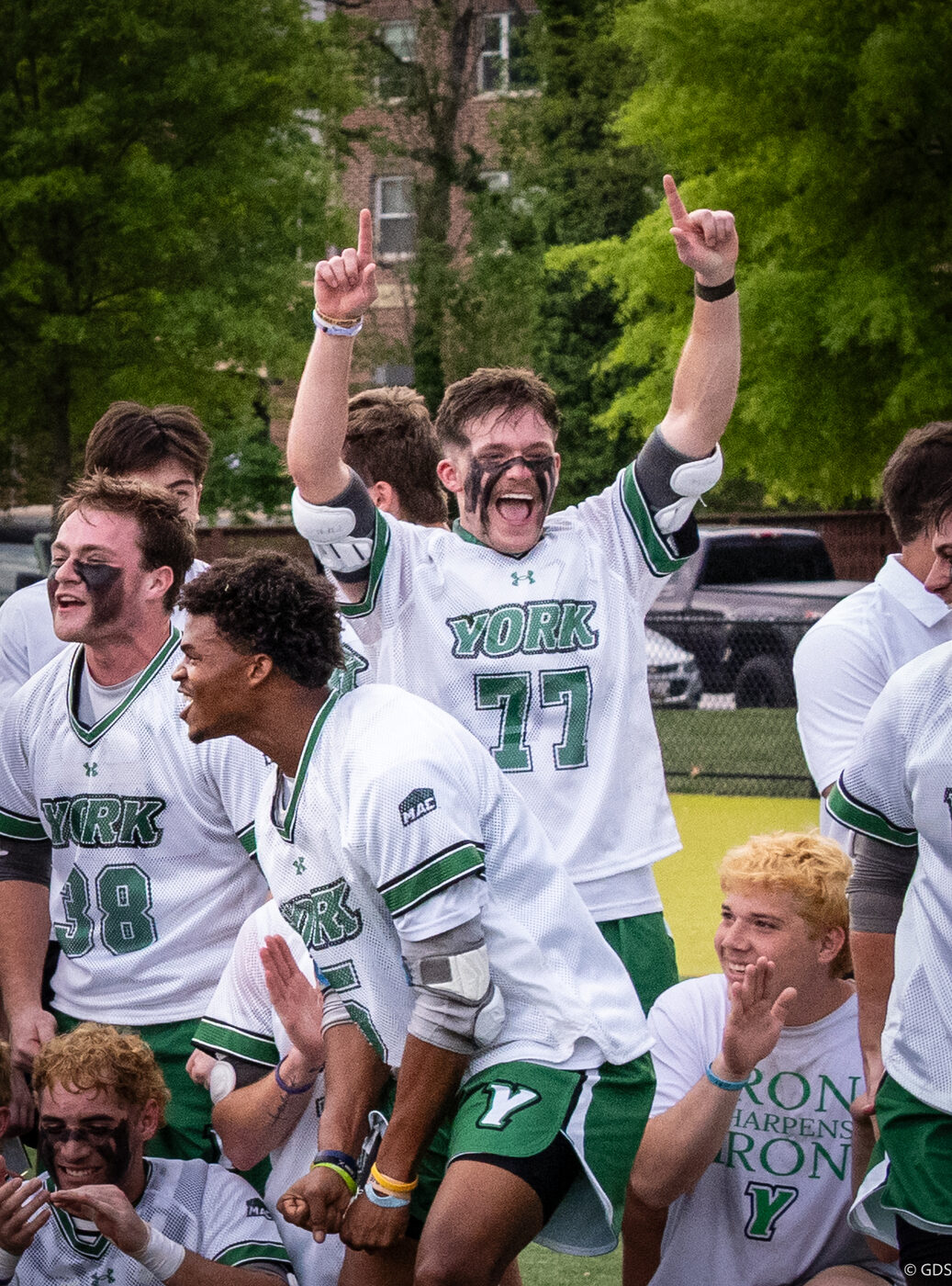 Trey Snodgrass and his York teammates, face paint on and arms raised, celebrating their MAC championship