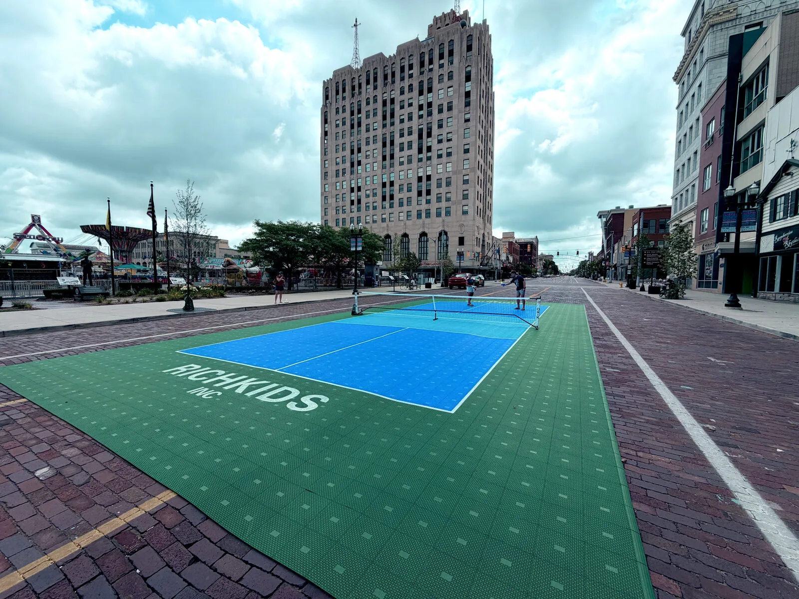 Pop-up pickleball court on the brick pavers of Saginaw Street in downtown Flint on a cloudy summer day