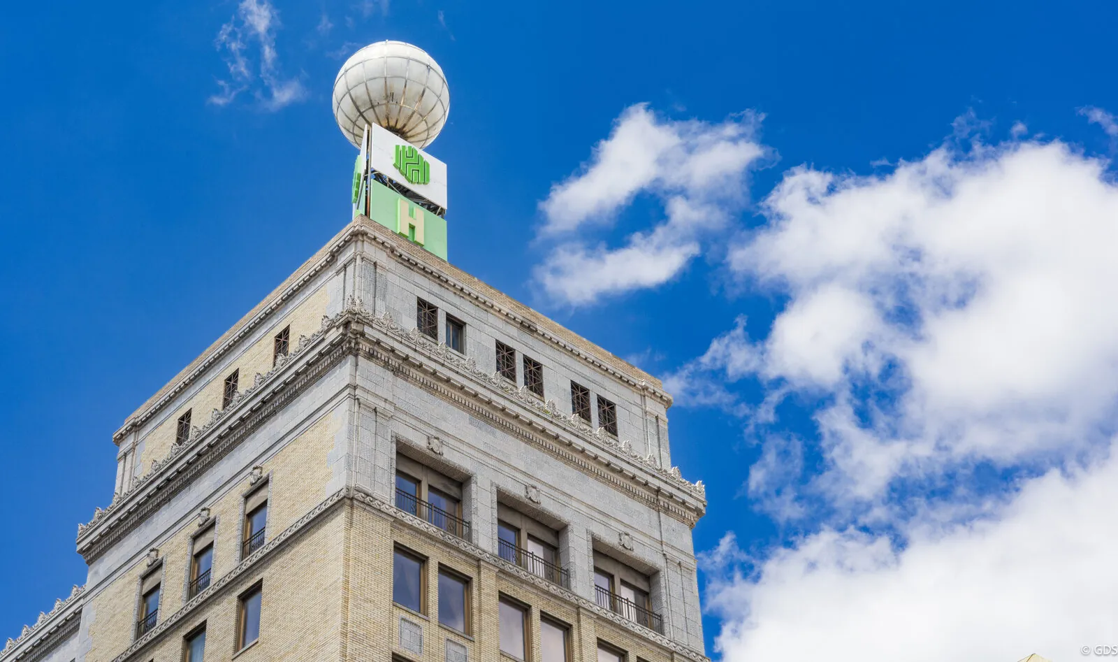 A historic downtown Flint building topped with an illuminated globe against a bright blue sky