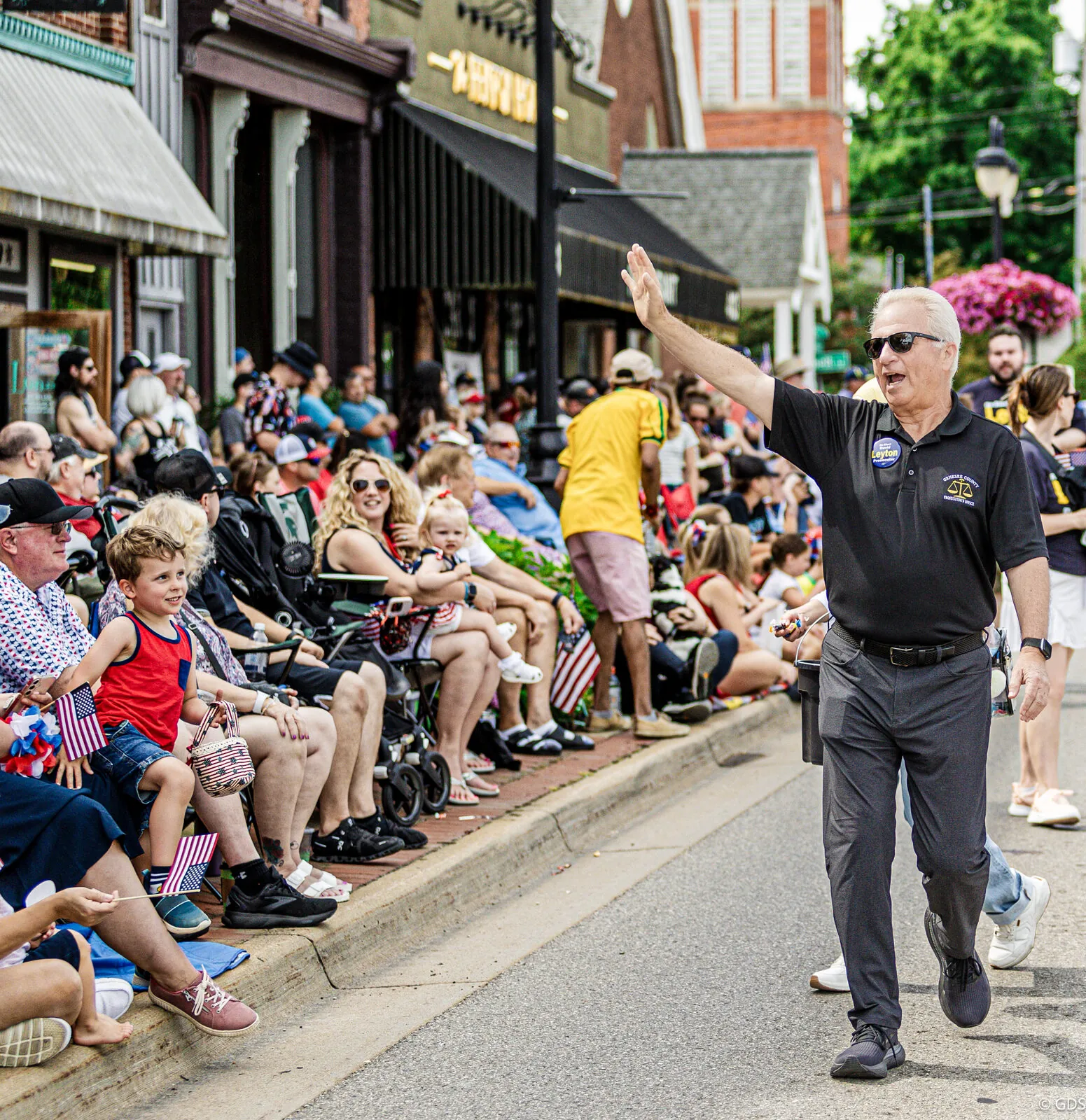 Genesee County Prosecutor David Leyton waving to the crowd while walking the Fenton Independence Day parade