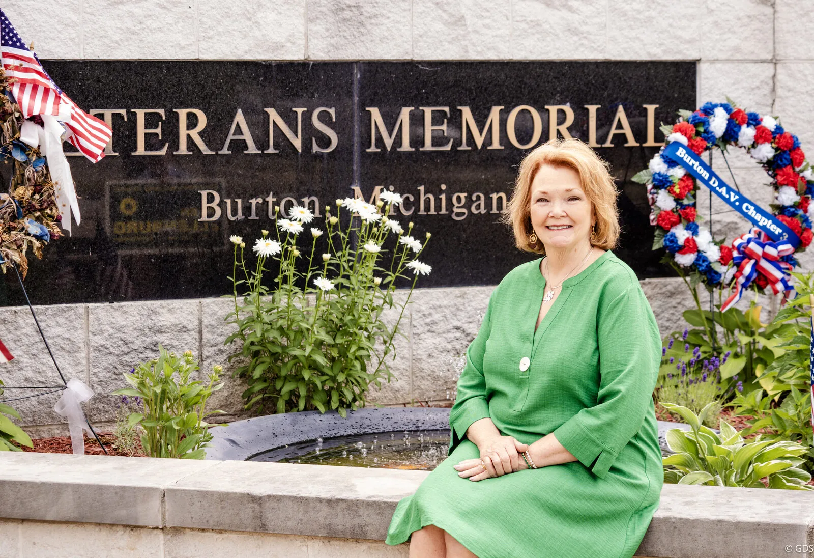 A candidate seated at the Burton, Michigan Veterans Memorial beside a memorial wreath