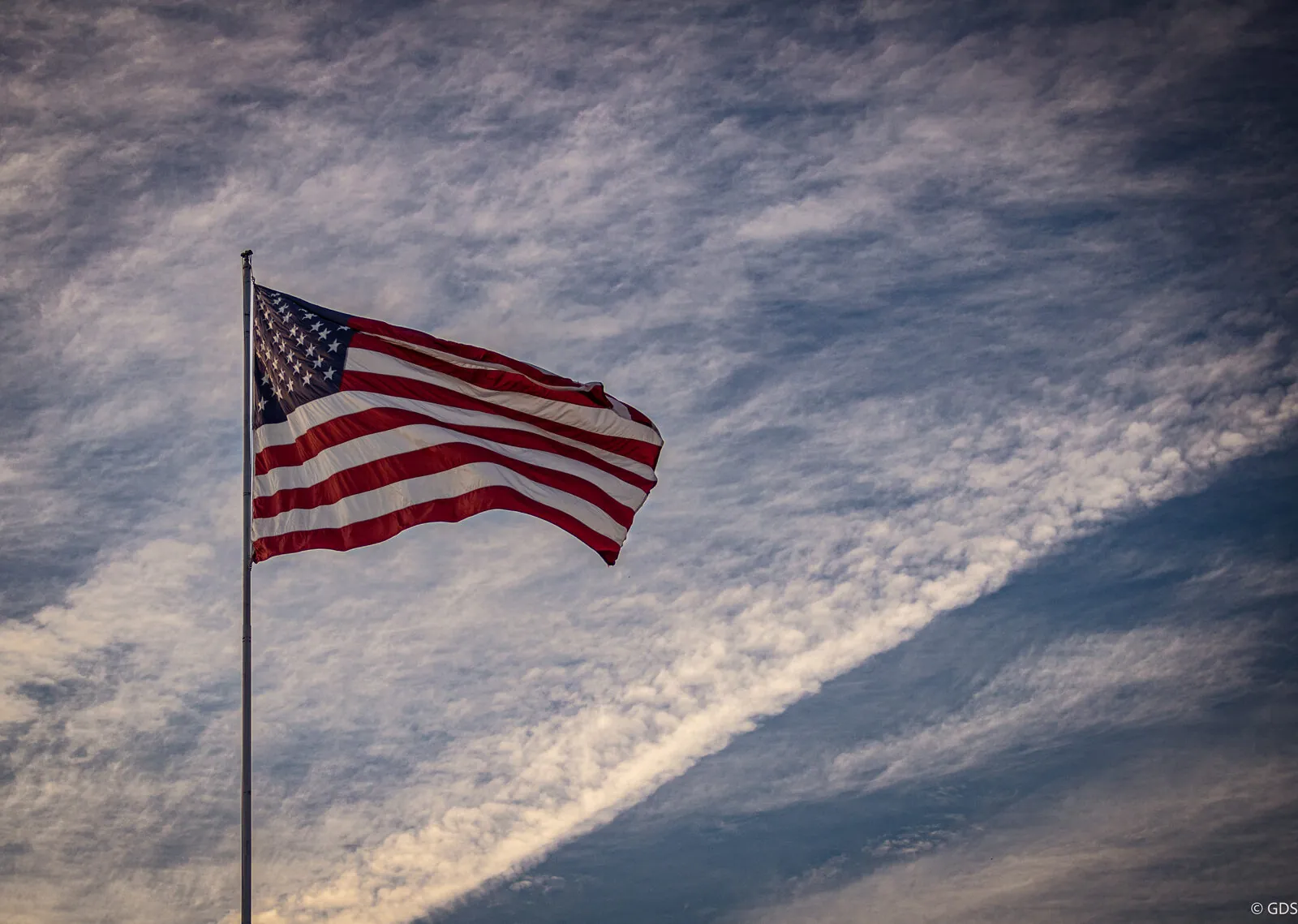 An American flag snapping against a streaked dusk sky