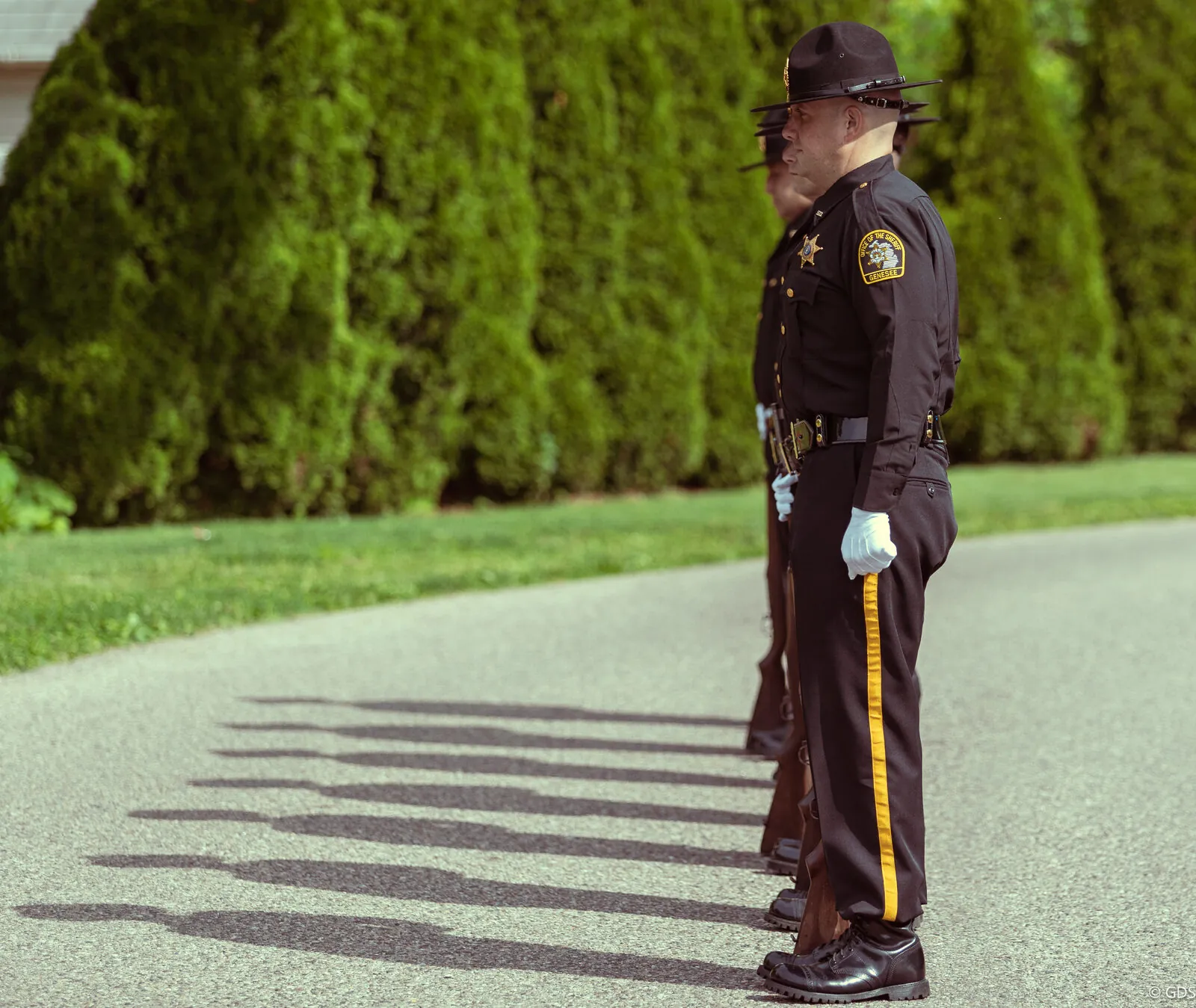 An honor guard standing at attention, long shadows — Swartz Creek parade