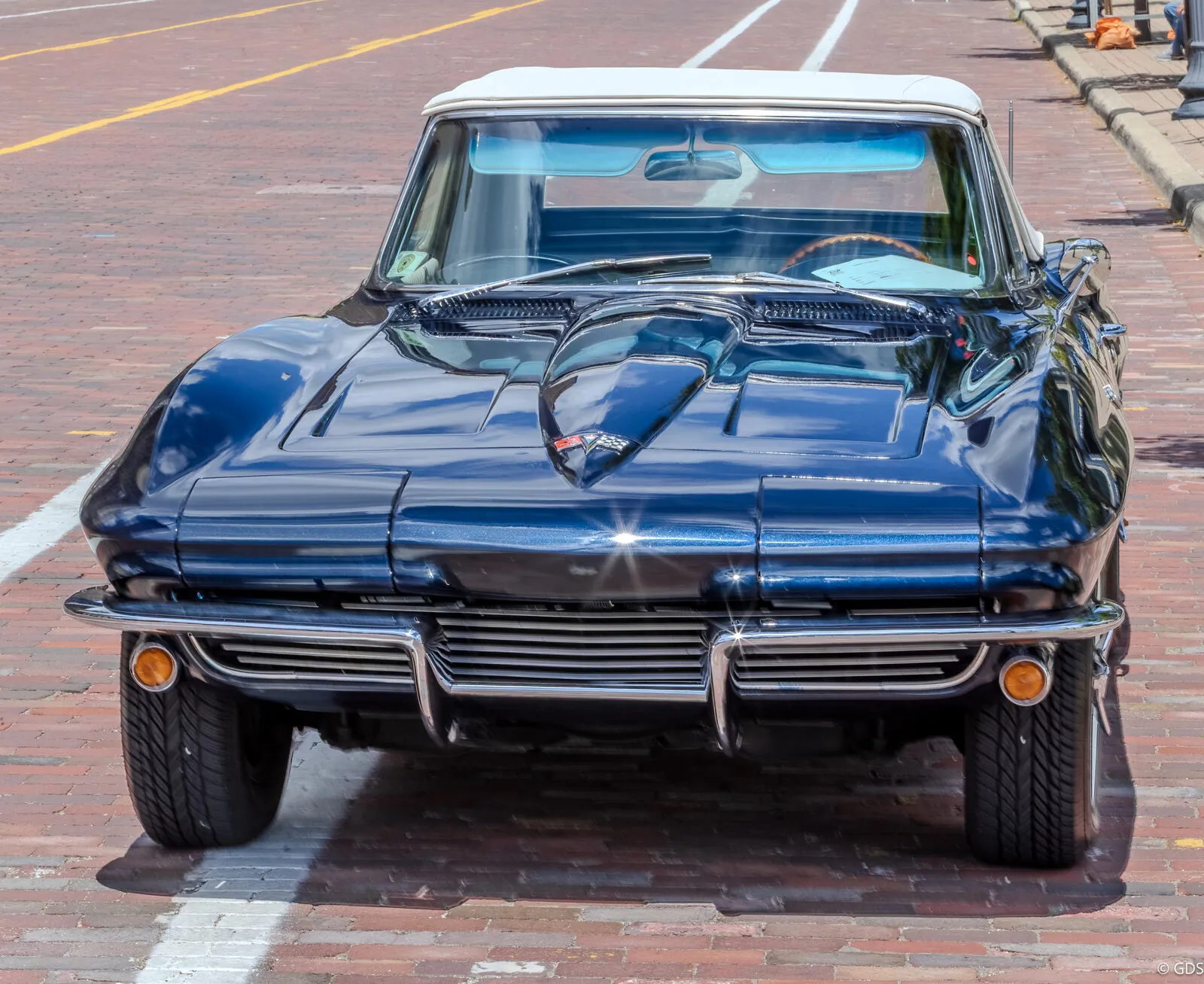 A vintage Chevrolet Corvette Stingray parked on a brick downtown street