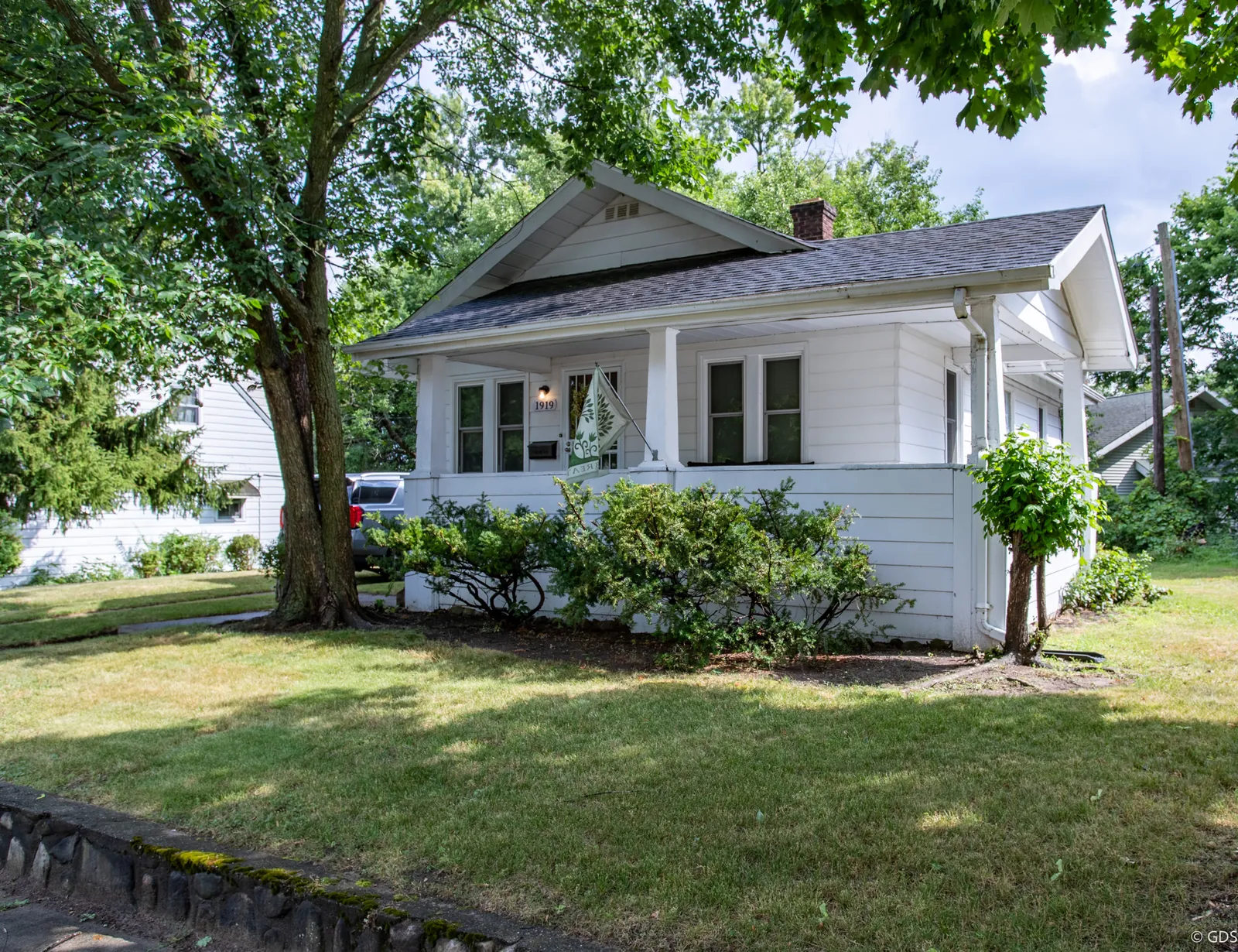 White Craftsman bungalow at 1919 Cartier Street shaded by a mature maple on a summer afternoon