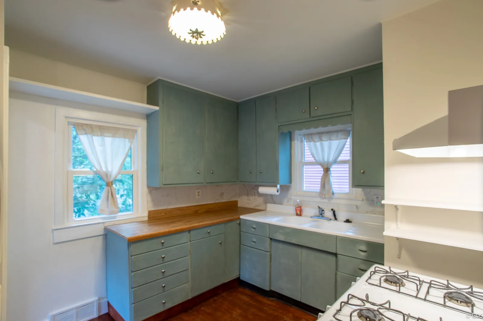 Vintage kitchen with sage-green cabinets, butcher-block counter, and original farmhouse sink — 1919 Cartier Street
