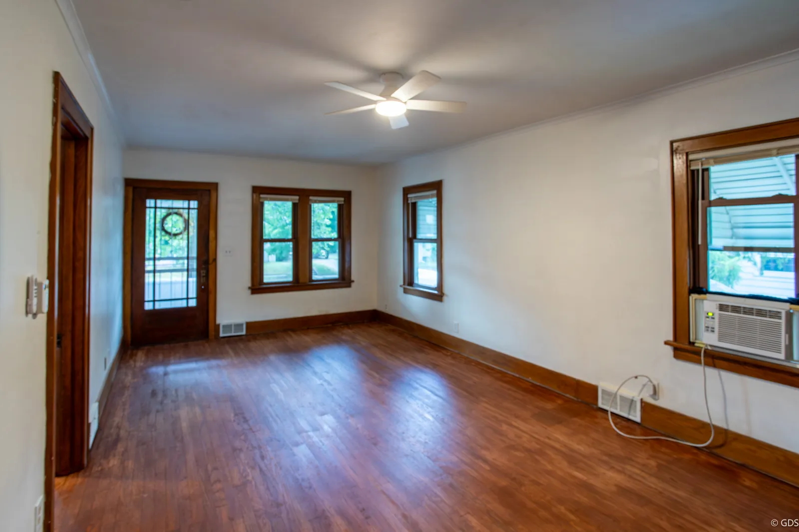 Sunlit living room with refinished hardwood floors and original wood trim — 1919 Cartier Street