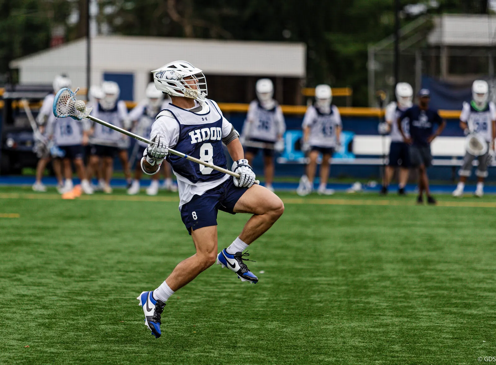 College lacrosse — a Hood College midfielder carries the ball upfield