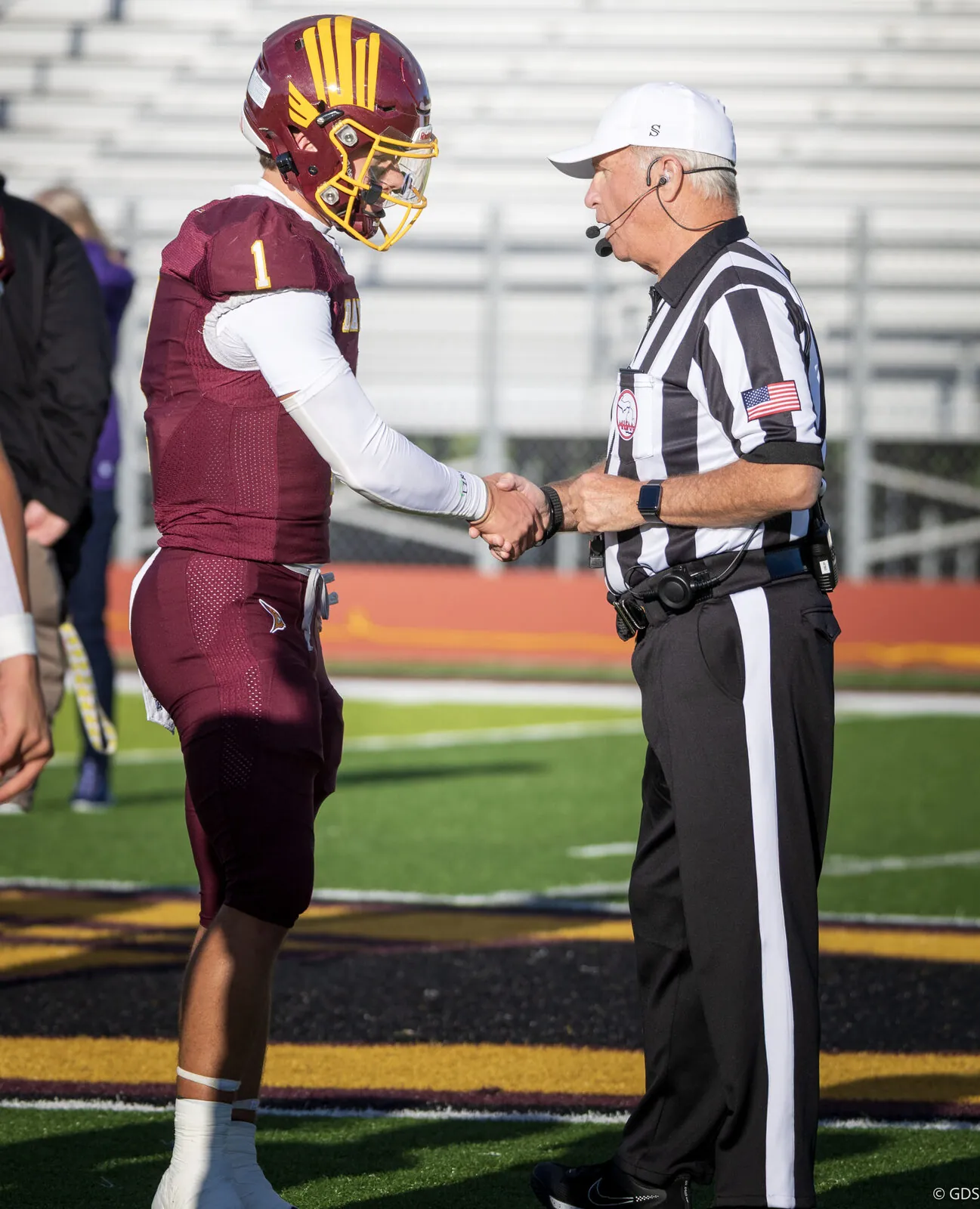 High school football captain shaking hands with the official at midfield before kickoff