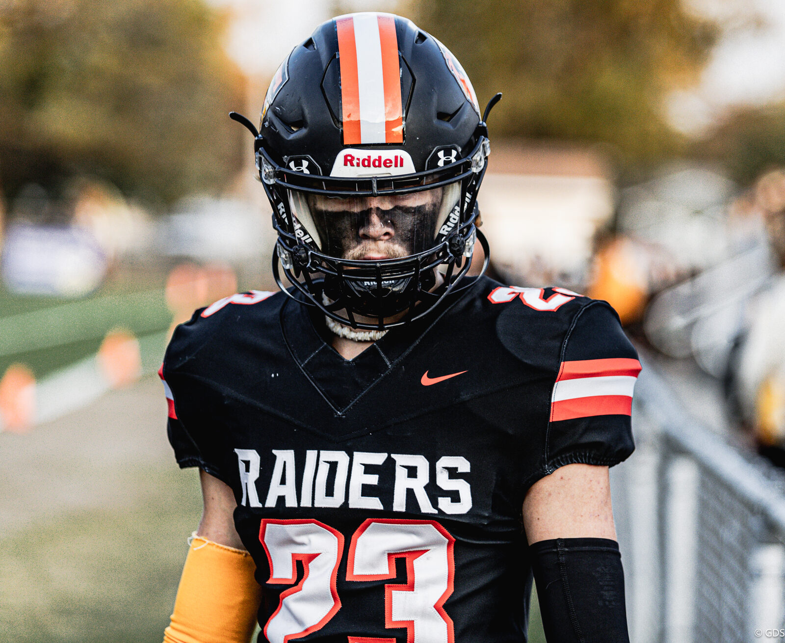 High school football — a Flushing Raiders player heads onto the field at dusk