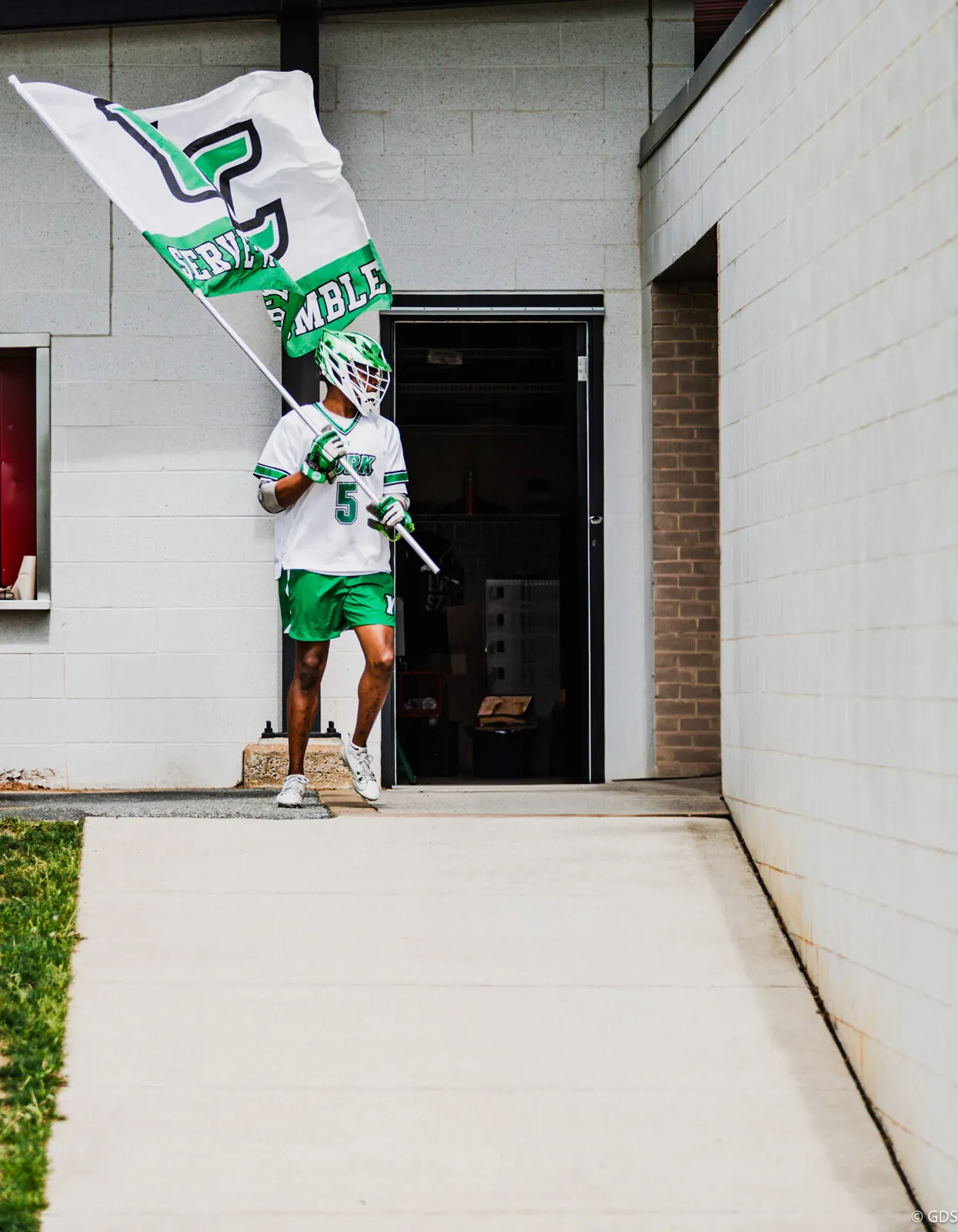 A lacrosse player carries the team flag out for pregame introductions at the MAC championship