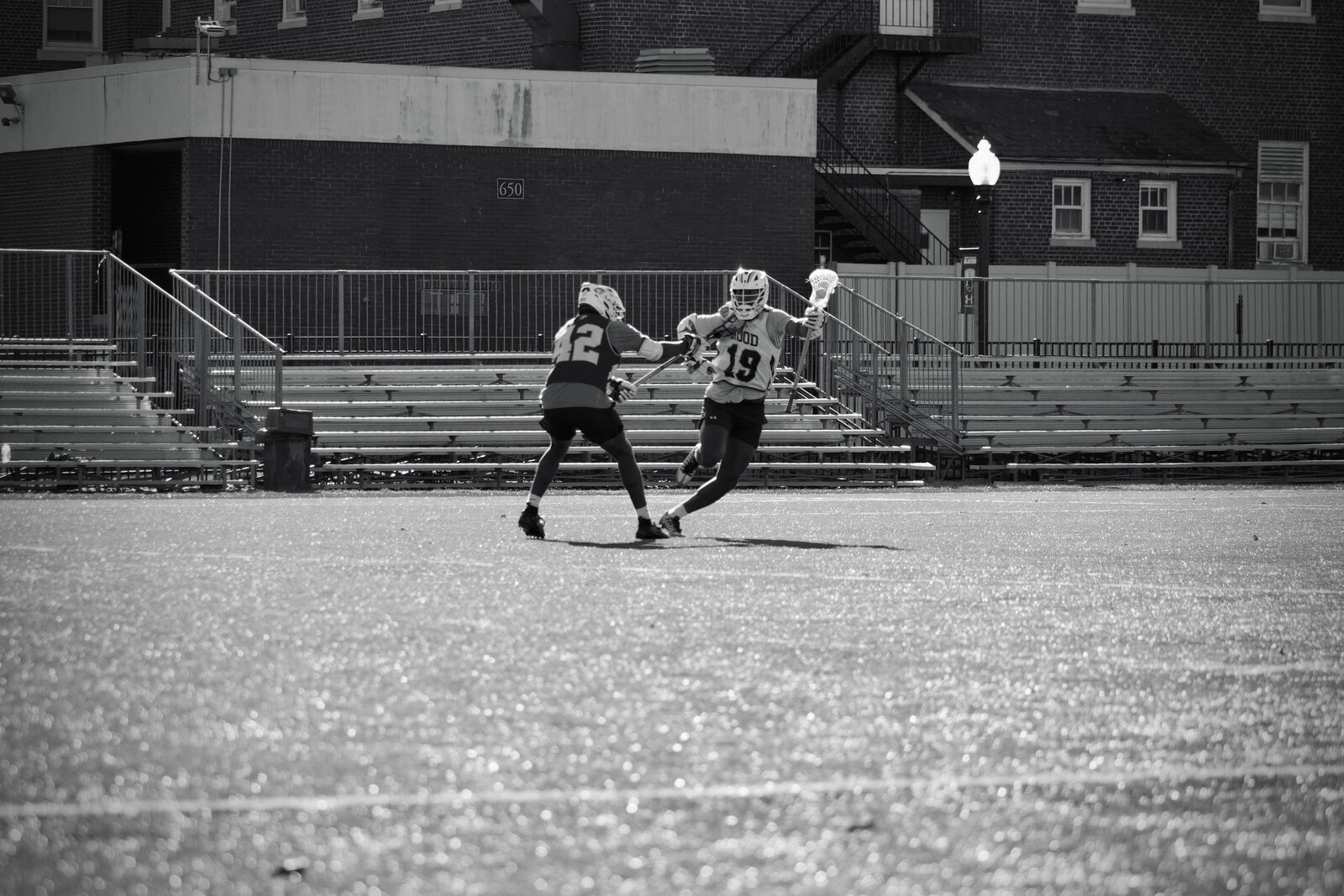 Black-and-white college lacrosse action at midfield