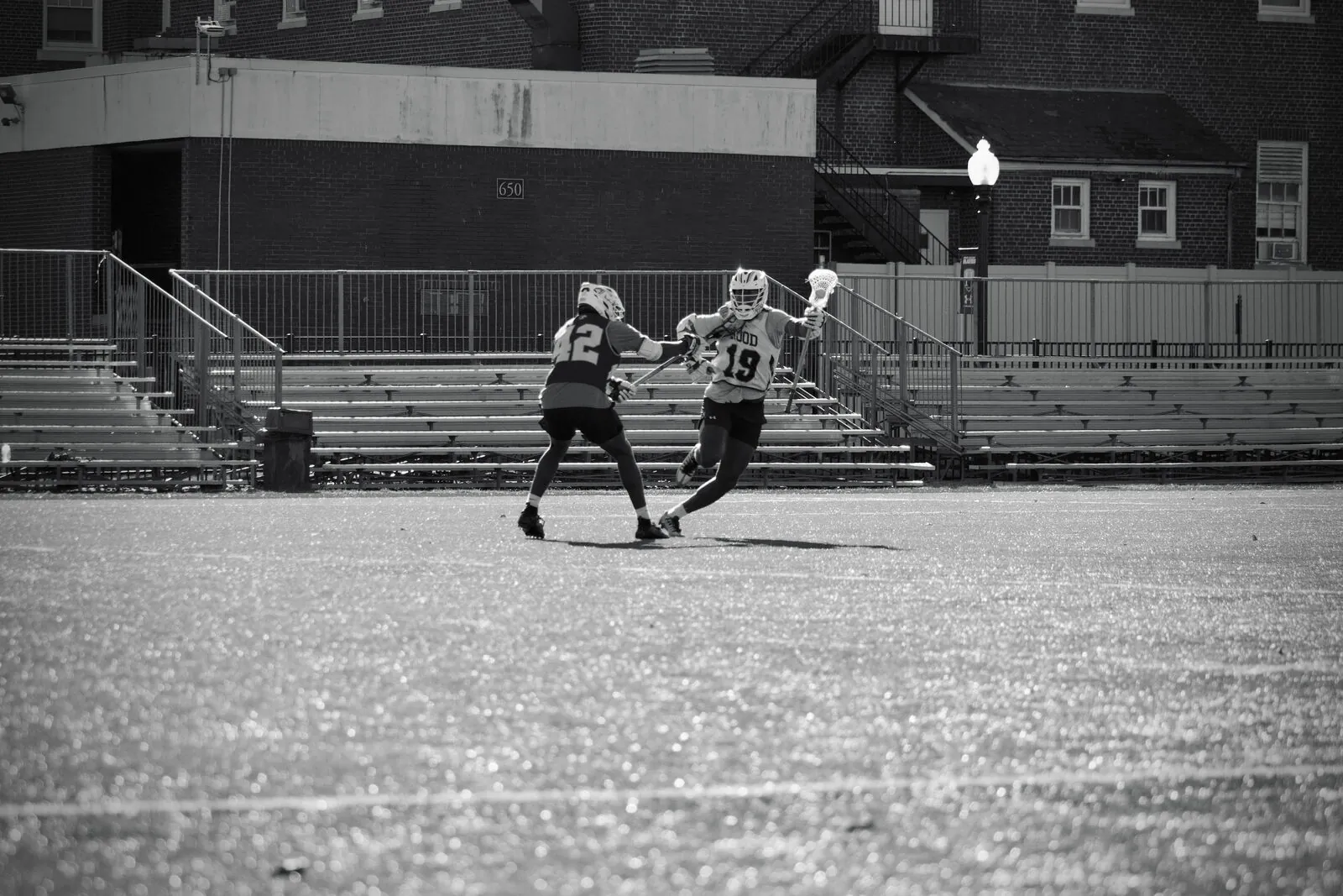 Black-and-white college lacrosse action at midfield