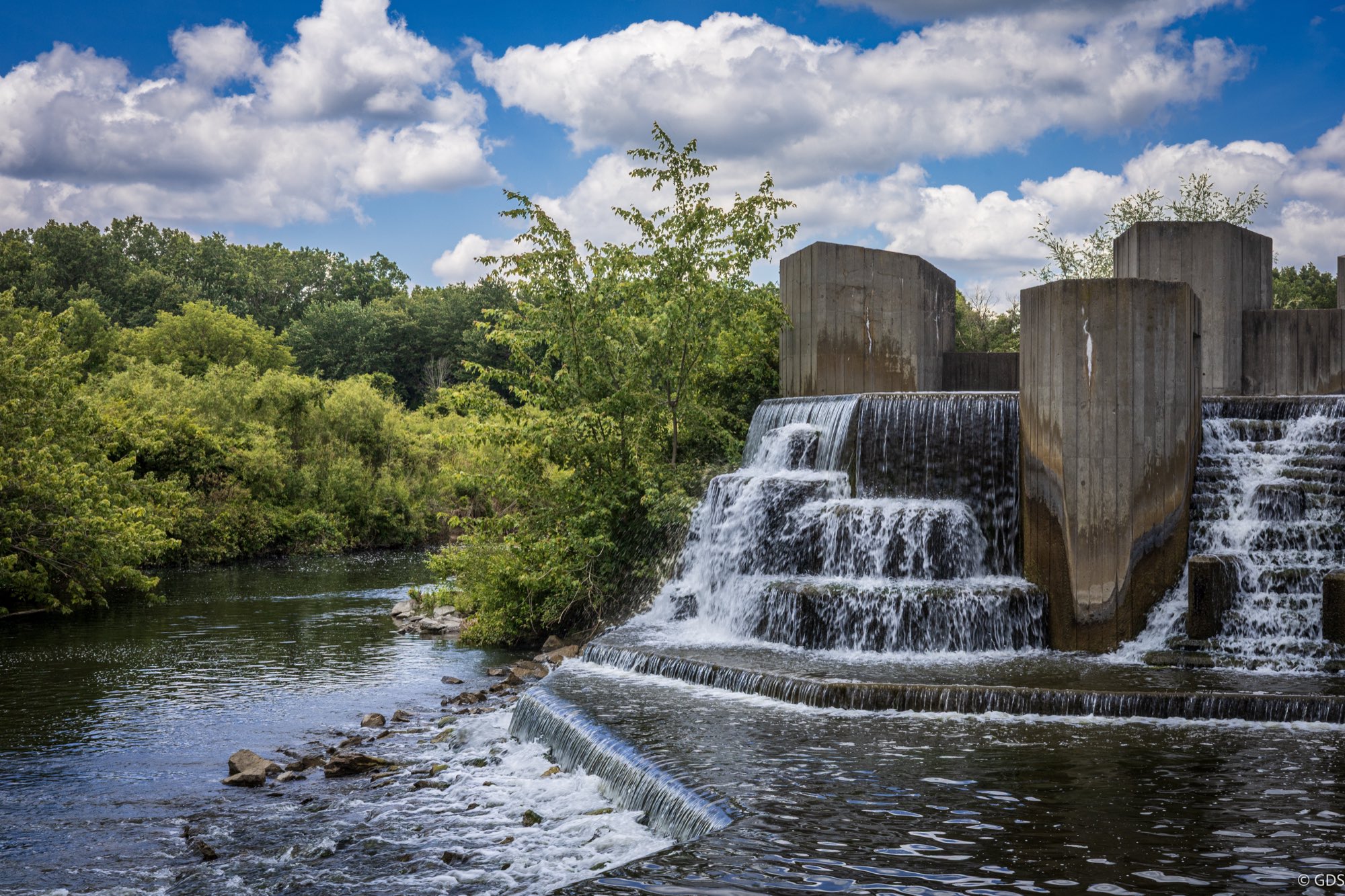 Stepping Stone Falls on the Flint River cascading over tiered concrete steps, framed by deep summer green